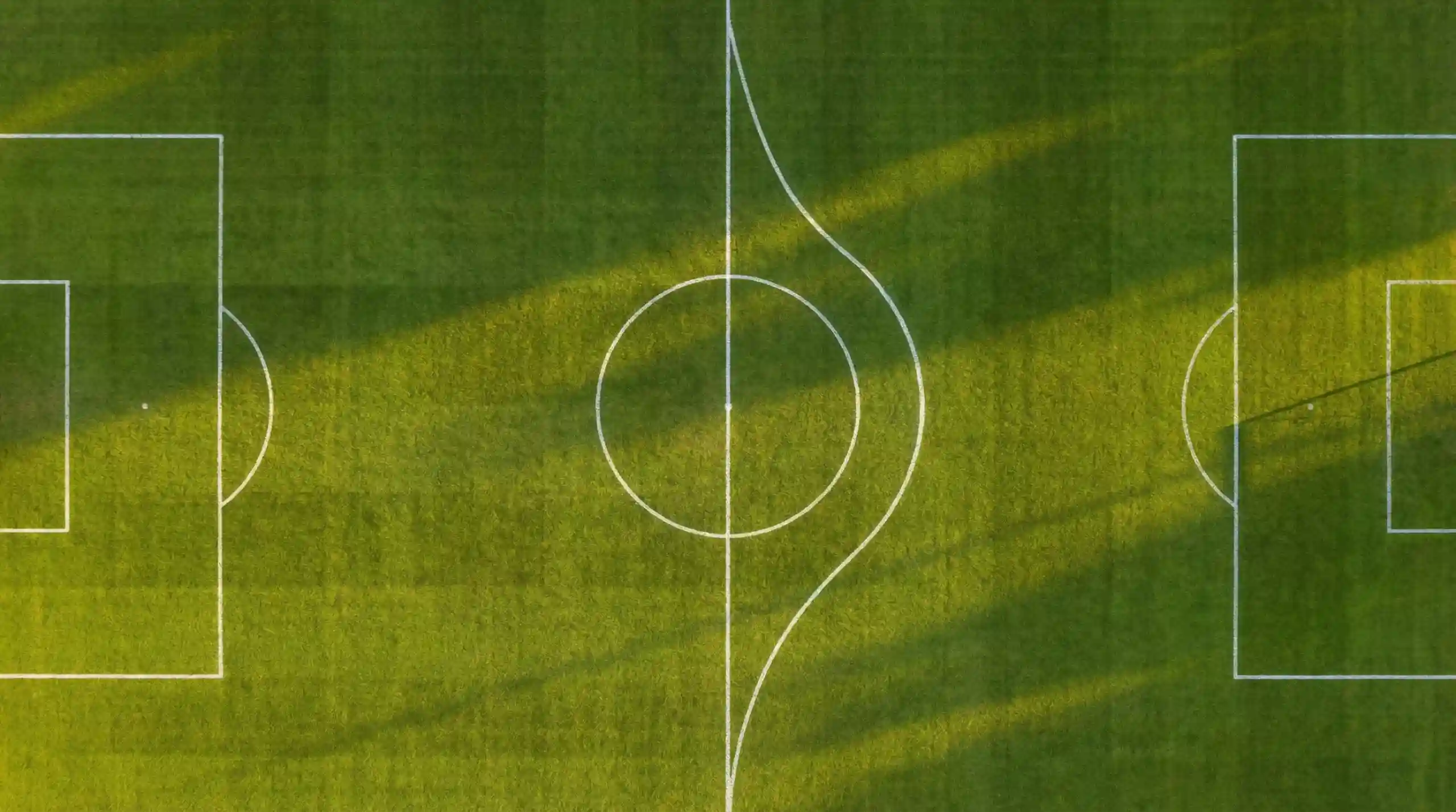 Due percorsi diversi su un campo da calcio visti dall'alto al tramonto
